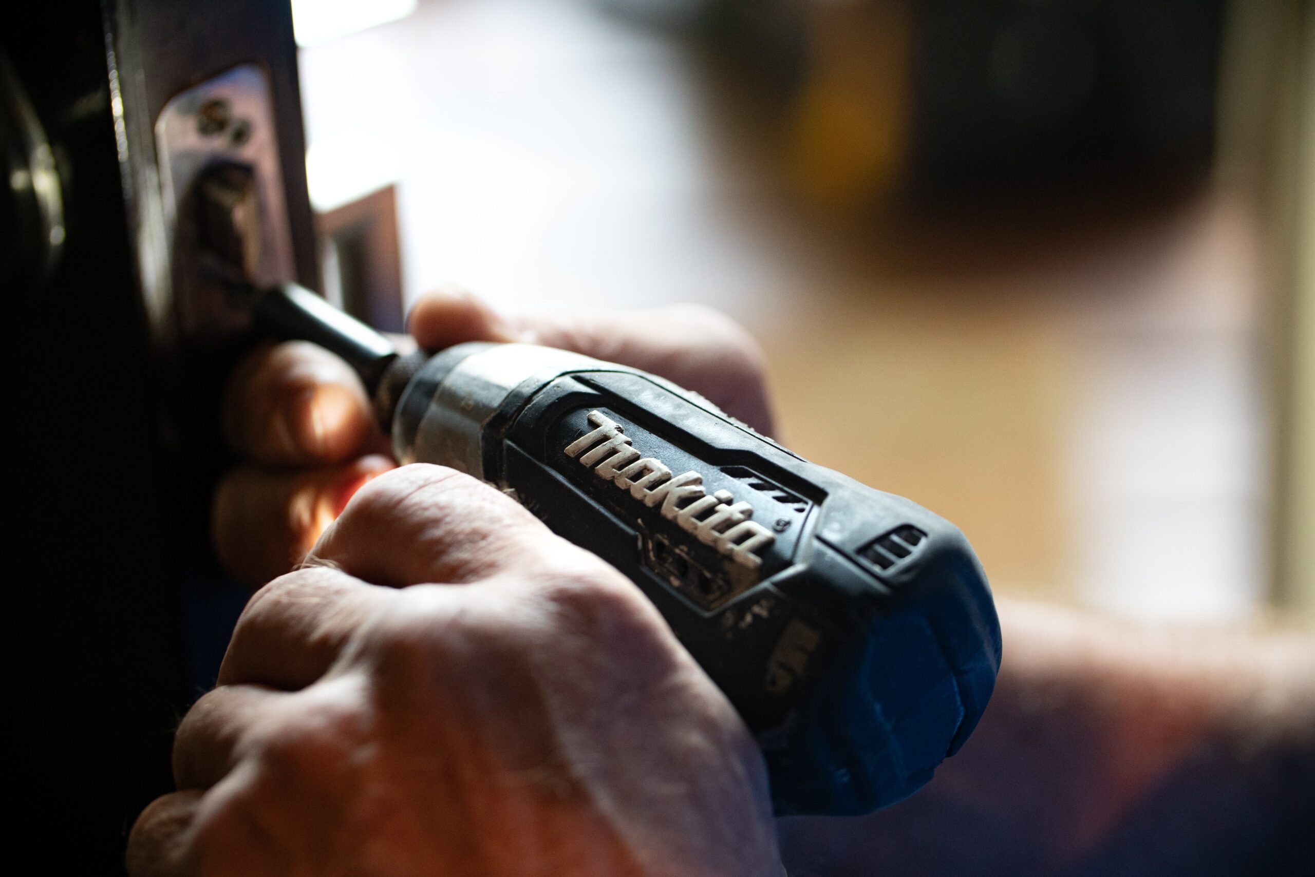 A hand holding a drill to illustrate a side job for real estate agents