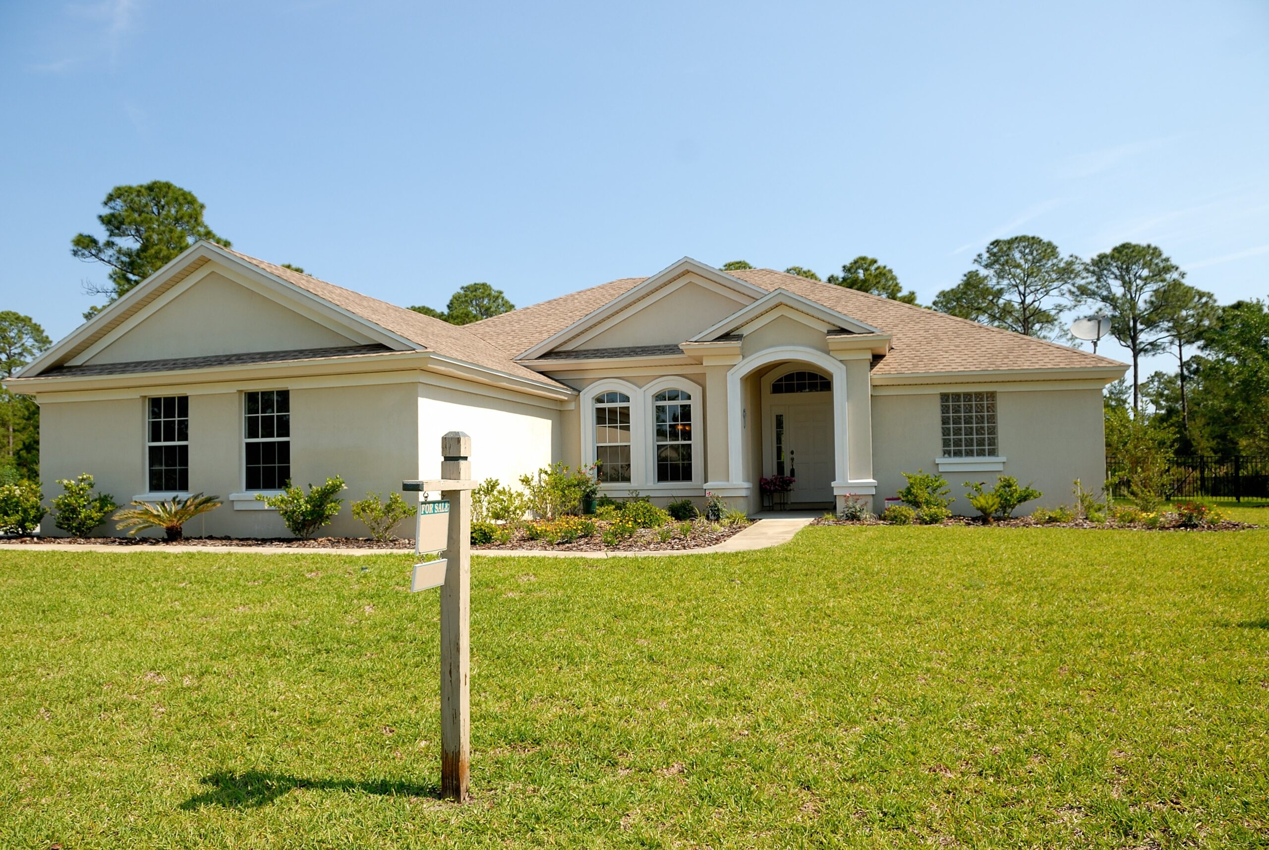 Home with a for sale sign hanging in the front yard 