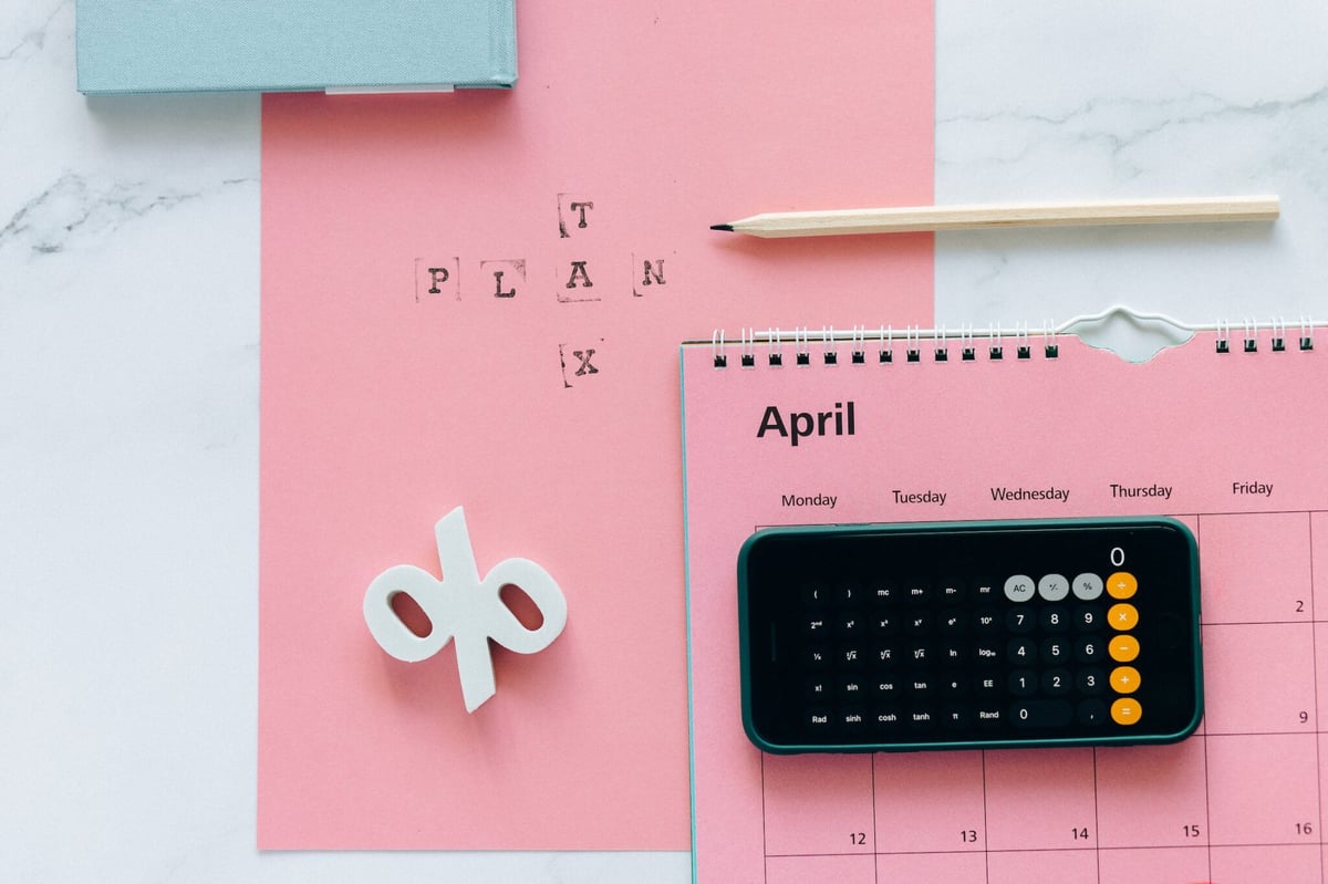 A-planner-a-phone-and-a-pink-paper-to-calculate-the-percentage-of-taxes-2048x1365
