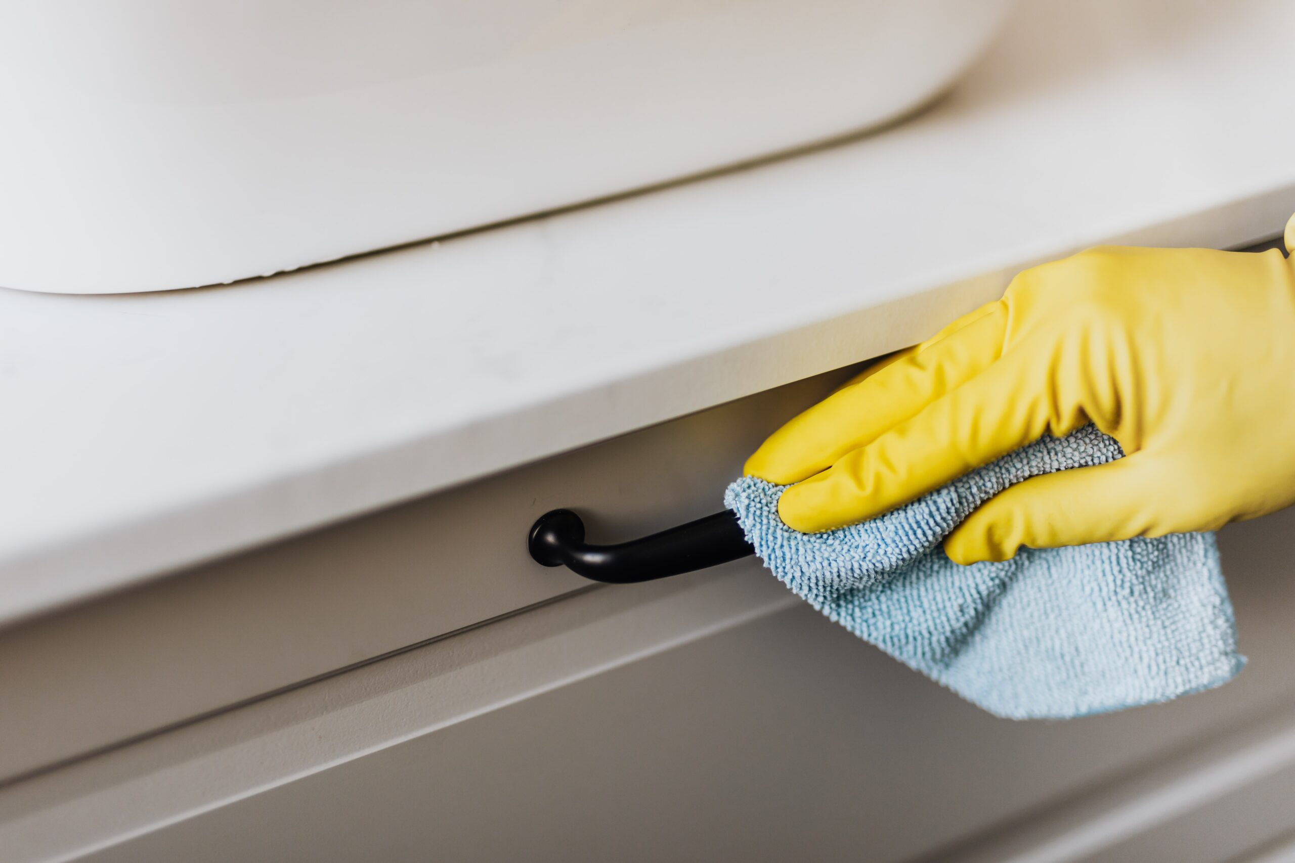 A rubber-gloved hand cleaning a handle as an example of an item on a property management preventative maintenance checklist