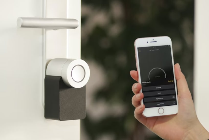 A hand holding a cell phone up to a smart lock 