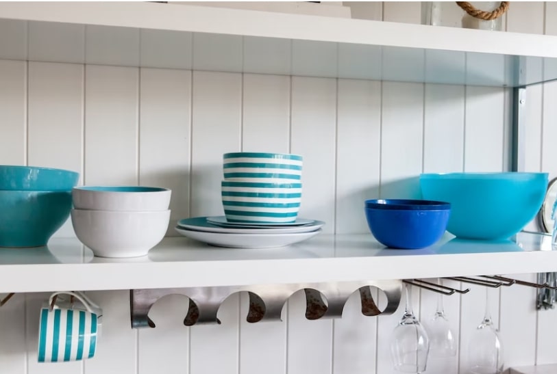 Blue and blue-and-white striped dinnerware on a kitchen shelf 