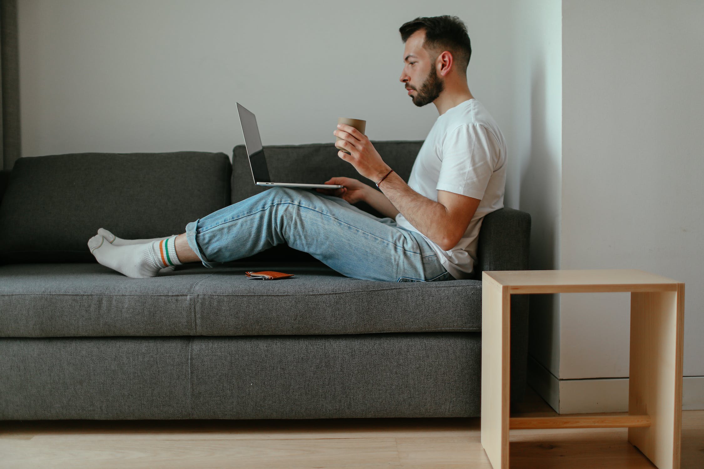 Male person sitting on a sofa using a laptop 